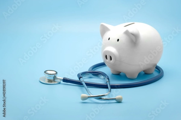 Fototapeta Piggy bank with stethoscope isolated on light blue background with copy space. Health care financial checkup or saving for medical insurance costs concept.