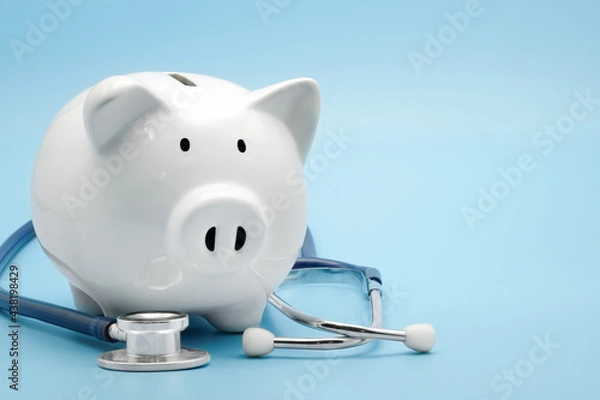 Fototapeta Piggy bank with stethoscope isolated on light blue background with copy space. Health care financial checkup or saving for medical insurance costs concept.
