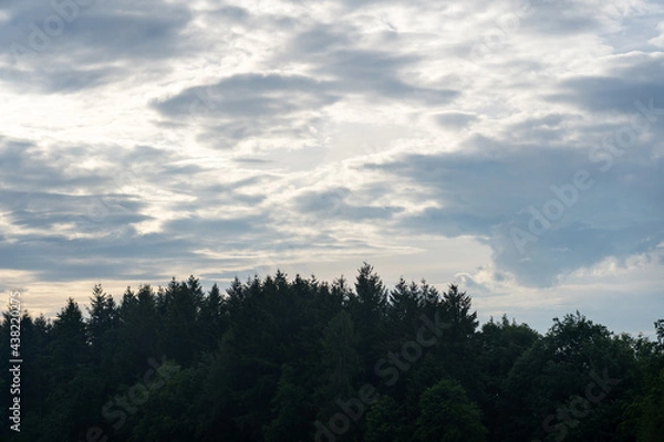 Obraz Wolken über einem Hügel mit Wald