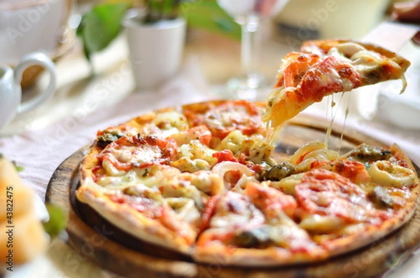 Obraz Oryginalna włoska pizza z owocami morza w plastrach na drewnianym talerzu