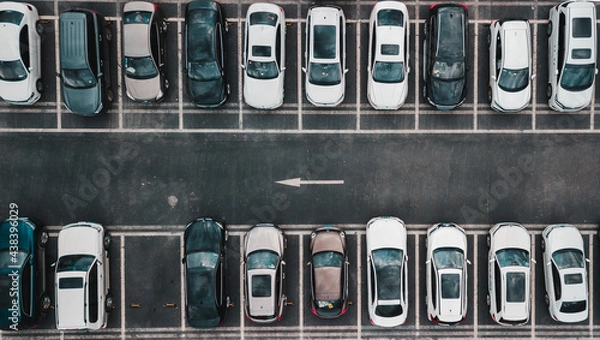 Fototapeta Top down aerial view on payed parking lot with parked cars and one way direction road. Perpendicular parked vehicles, different type of cars, roof view.