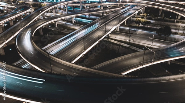 Fototapeta Night long exposure illumination of elevated multilevel traffic junction. Modern development of backlighted roads and current new infrastructure in China, Chengdu. Aerial drone point of view.
