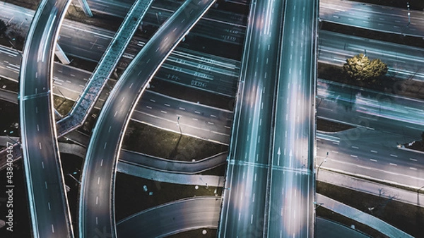 Fototapeta Night long exposure illumination of elevated multilevel traffic junction. Modern development of backlighted roads and current new infrastructure in China, Chengdu. Aerial drone point of view.