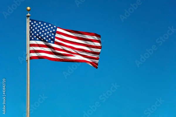 Obraz US American flag waving in the wind with beautiful blue sky in b