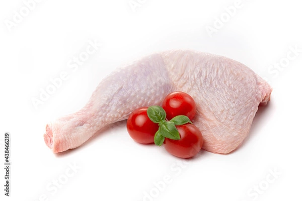 Obraz Raw chicken thighs with skin decorated with tomatoes and basil on a white background.
