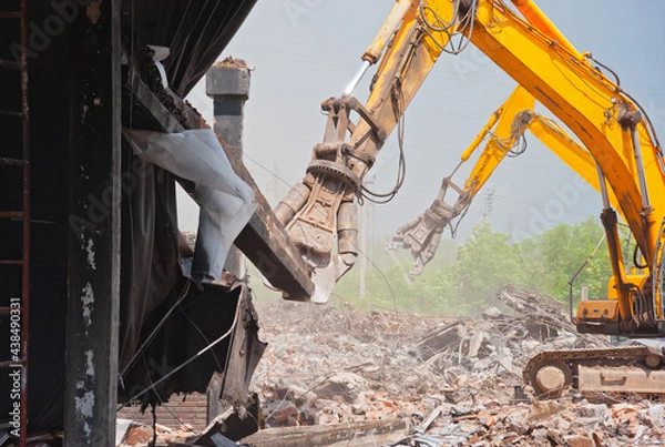 Fototapeta Two demolators destroy the building and remove the debris.