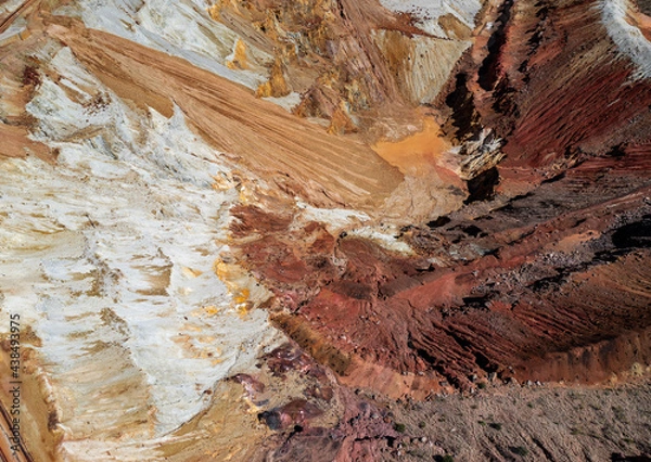 Fototapeta Aerial view of the inside of a mine in Arizona. Textured dirt in red, orange, white, and pink hues.