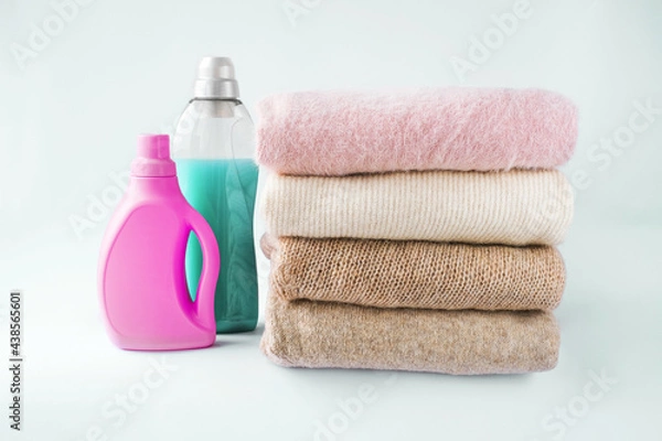 Fototapeta woolen clothes of light shades, folded on a white background with washing gel and rinses. mockup