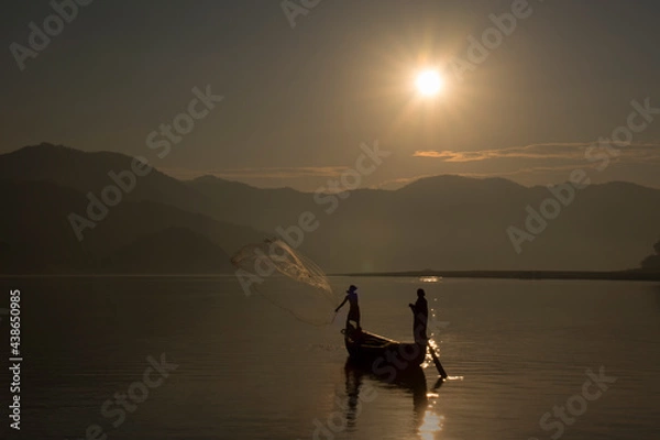 Fototapeta Fishermen throwing the fishing net in the river to catch the fish during sunrise