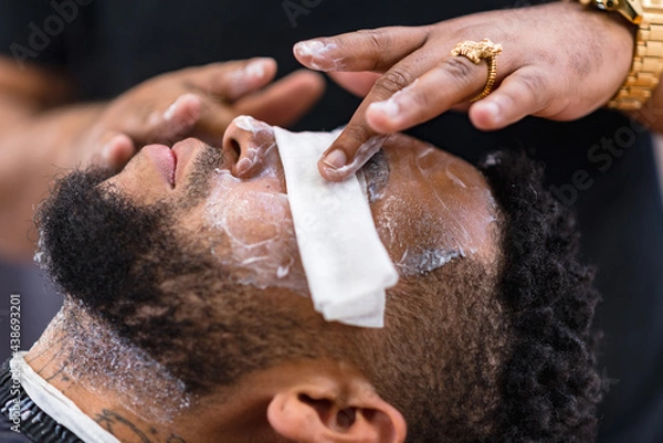 Fototapeta applying cleansing cream in peluqueria latina to proceed to the haircut. rings and watch in the hands of the barber.barber applying carefully  .