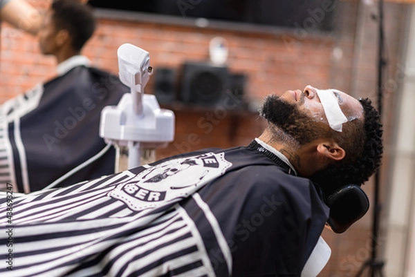 Fototapeta cleansing skin in latin hairdressing salon, to open pores for a better shave.with razor and hair clipper. .