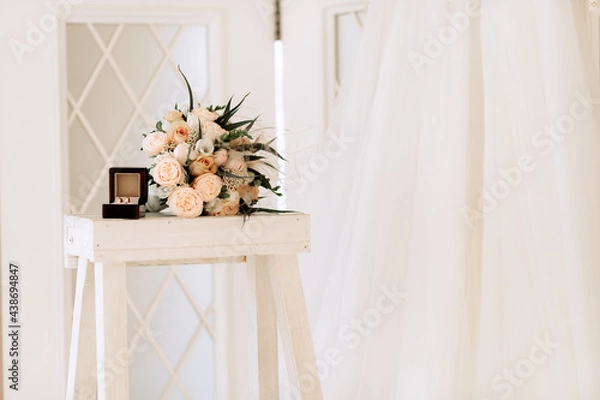 Obraz Wedding gold rings in a box next to a bouquet, on a light background.