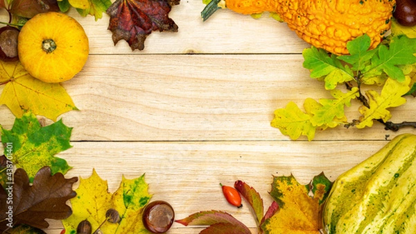 Fototapeta Flat lay autumn. Natural harvest with orange pumpkin, fall dried leaves, red berries and acorns, chestnuts on wooden background in shape frame. For seasonal offers and holiday post card, top view.