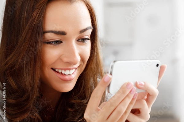 Fototapeta Pretty young woman using mobile phone