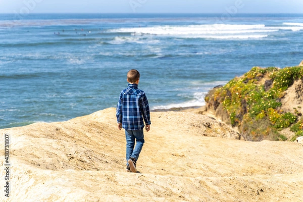 Fototapeta Boy looking at ocean from cliff