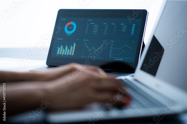 Fototapeta Asian business woman reviewing data in financial charts and graphs with tablet. Accounting