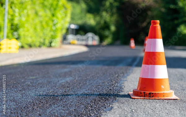 Fototapeta Construction cones marking part of road with a layer of fresh asphalt.