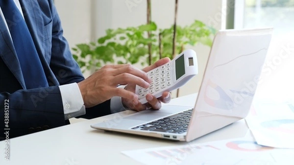 Obraz パソコンの前で電卓を操作するサラリーマン男性