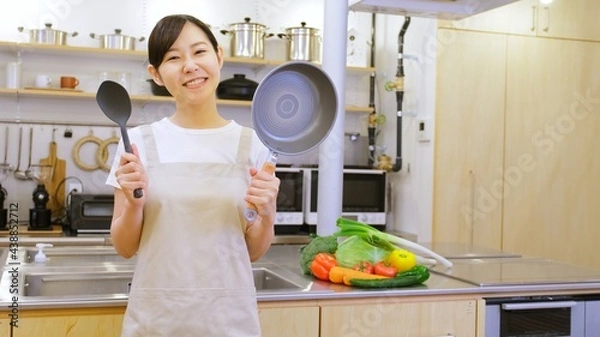 Fototapeta フライパンを持ちカメラ目線でほほ笑む家事代行の女性作業員
