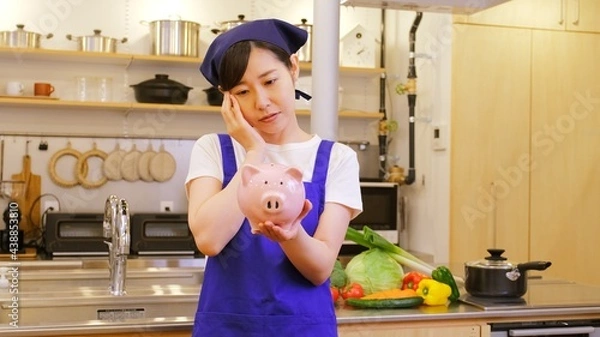 Obraz 豚の貯金箱をもち悩む家事代行の女性作業員