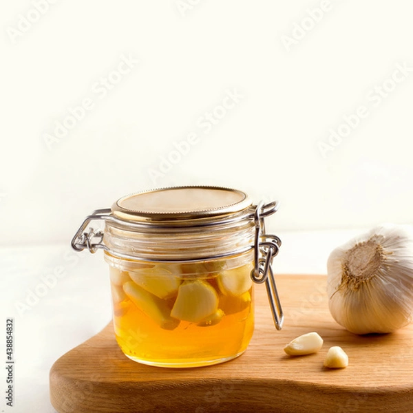 Obraz Honey with garlic on a white plate next to the ingredients. Copy space