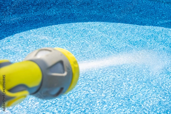 Fototapeta Close-up of filling the water into an empty swimming pool by garden hose