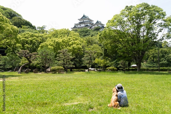 Obraz 広場で仲良く片寄せ合って座ってる女性とゴールデンレトリーバー