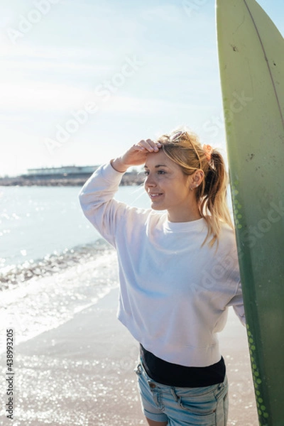 Fototapeta Caucasian girl looking at the ocean with surfboard