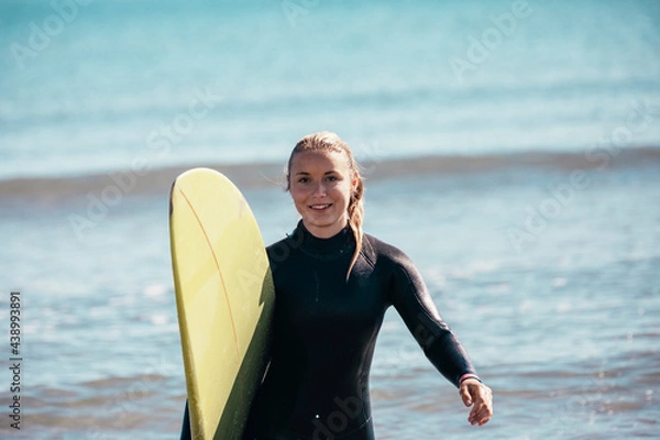 Fototapeta Portrait of a young girl on the beach with a surfboard.