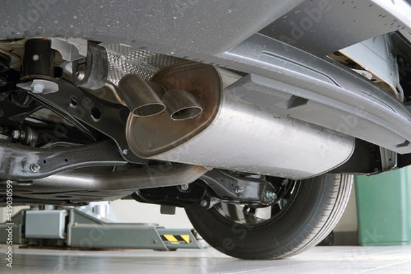 Fototapeta A muffler installed on a modern car. Bottom view of the car.