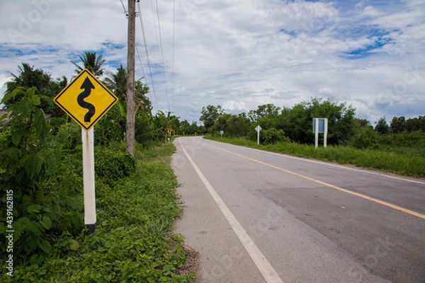 Fototapeta Road sign curved reminds the motorists and vehicles while driving with yellow sign reflecting light to be visible at night at the roadway in countryside of Thailand