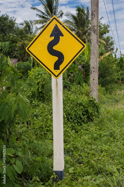 Obraz Road sign curved reminds the motorists and vehicles while driving with yellow sign reflecting light to be visible at night at the roadway in countryside of Thailand