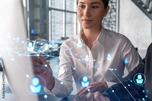 Fototapeta Businessman and businesswoman in formal wear working together looking for new employees to hire for international business consulting. HR, social media icons over modern panoramic office background