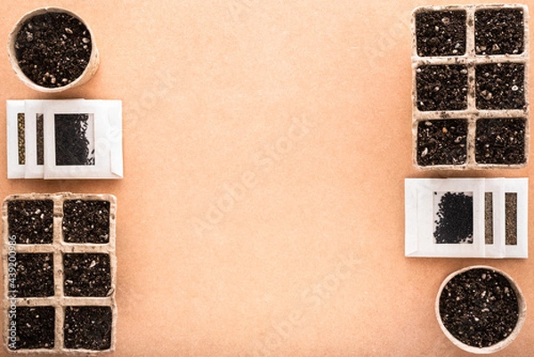 Fototapeta Biodegradable peat pots and trays with potting soil and seeds in small envelopes for sowing, on a raw surface with copy space, eco-friendly seed starter 