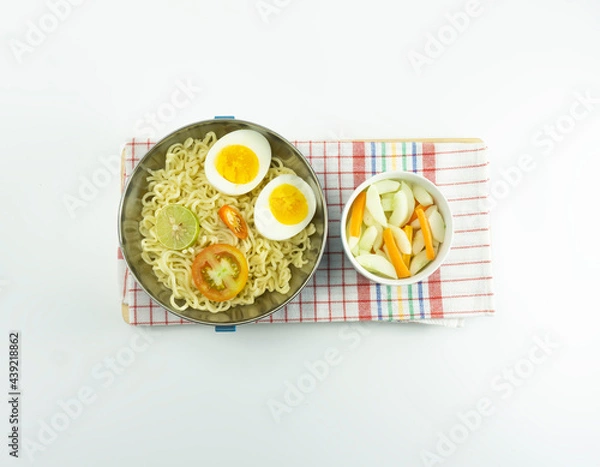 Fototapeta Indonesian Warm noodles served with fresh tomatoes and meatballs on a white round bowl and pickles on a white bowl on a white background