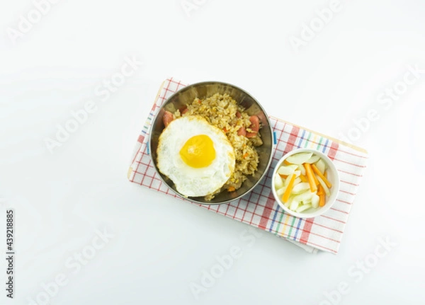 Fototapeta Indonesian Fried rice served with fresh tomatoes and meatballs in a stainless round bowl and pickles on a white bowl on a white background
