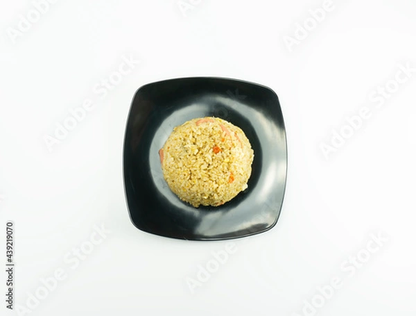 Fototapeta Nasi Goreng or Indonesian Fried rice served with fresh tomatoes and meatballs in a black tosca plate and pickles on a white bowl on a white background
