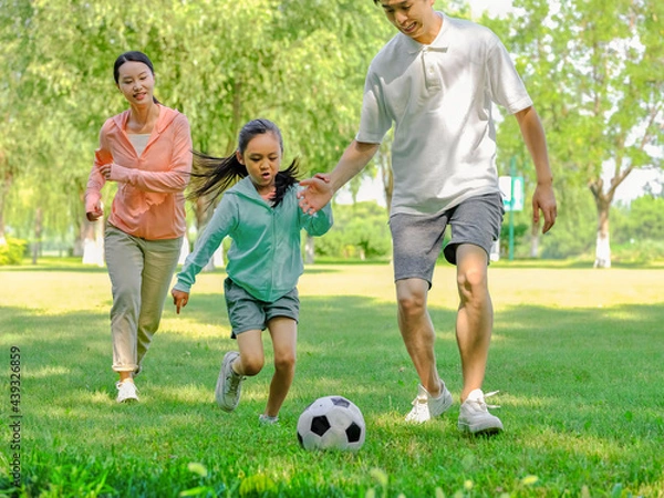 Obraz Happy family of three playing football in the park