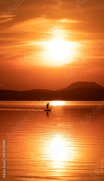 Fototapeta landscape with a man paddling on the lake in the evening