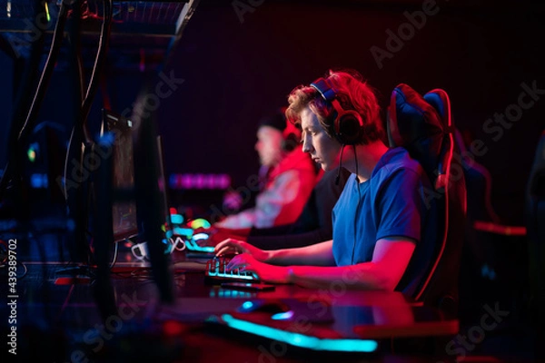 Fototapeta Professional esports players at an online game tournament. The cyber team plays computers and trains