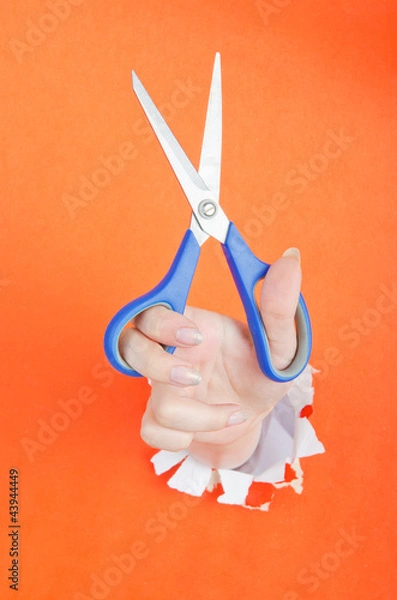 Fototapeta Hand with scissors from paper hole