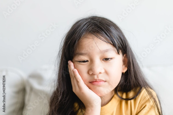 Fototapeta Asian kid girl toothache.kid suffering from toothache.TMD and TMJ healthcare Joint and Muscle Disorder.Asian child hand on cheek face as suffering from facial pain, mumps toothache.Dental health care.