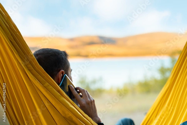 Obraz Person in a hammock making a call