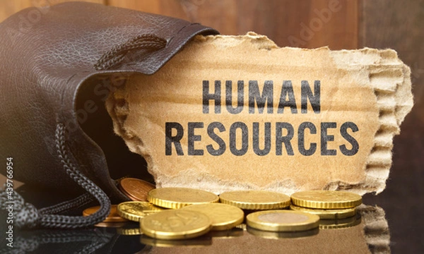 Fototapeta On the table is a bag of money from which sticks out cardboard with the inscription - HUMAN RESOURCES