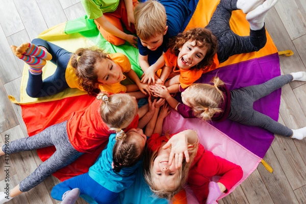 Fototapeta Cheerful children playing team building games on a floor