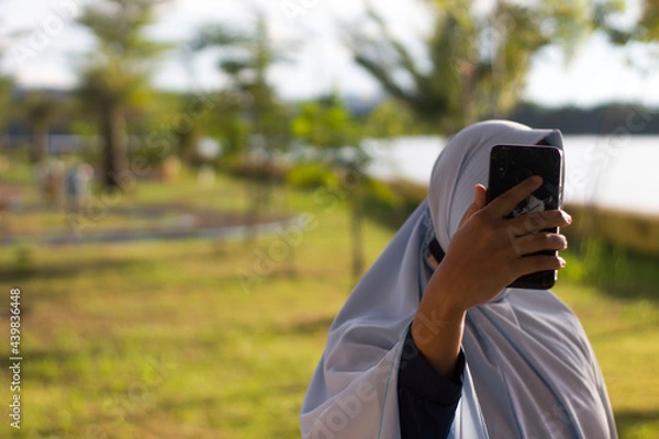Obraz Muslim Girl taking selfie by mobile phone at public park outdoor