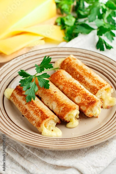 Fototapeta Fried rolls of bread and parmesan cheese with parsley on a plate on a white wooden background. Breakfast. Brunch. A delicious snack for gourmets. Selective Focus