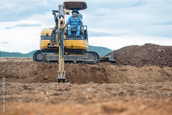 Fototapeta mini excavator digging soil with mountain background