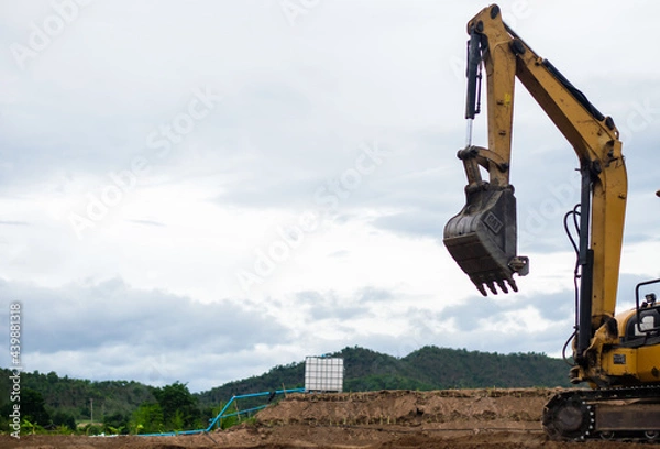 Fototapeta A mini excavator is digging the soil in the field.