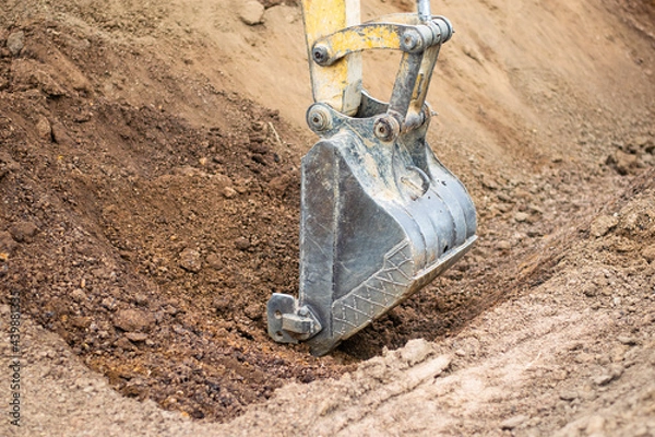 Fototapeta A mini excavator is digging the soil in the field.